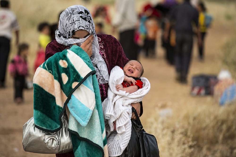 Una mujer cruza la frontera siria con su bebé.